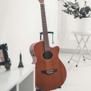 A classic acoustic guitar stands elegantly in a bright, minimalist indoor setting, surrounded by modern decor.